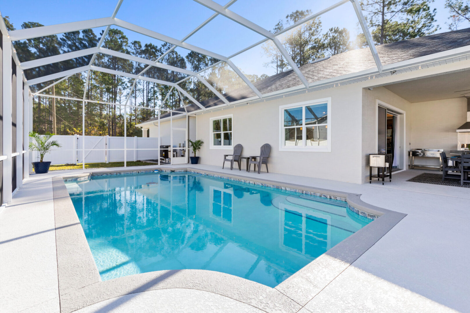 A pool with chairs and tables in the back yard.