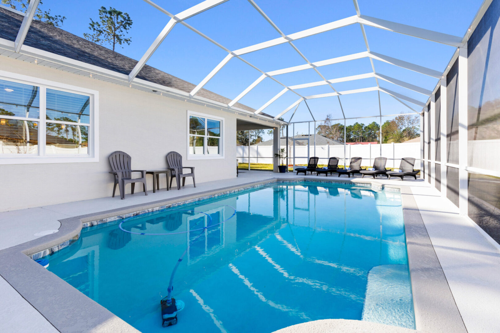 A pool with chairs and tables in the back yard.