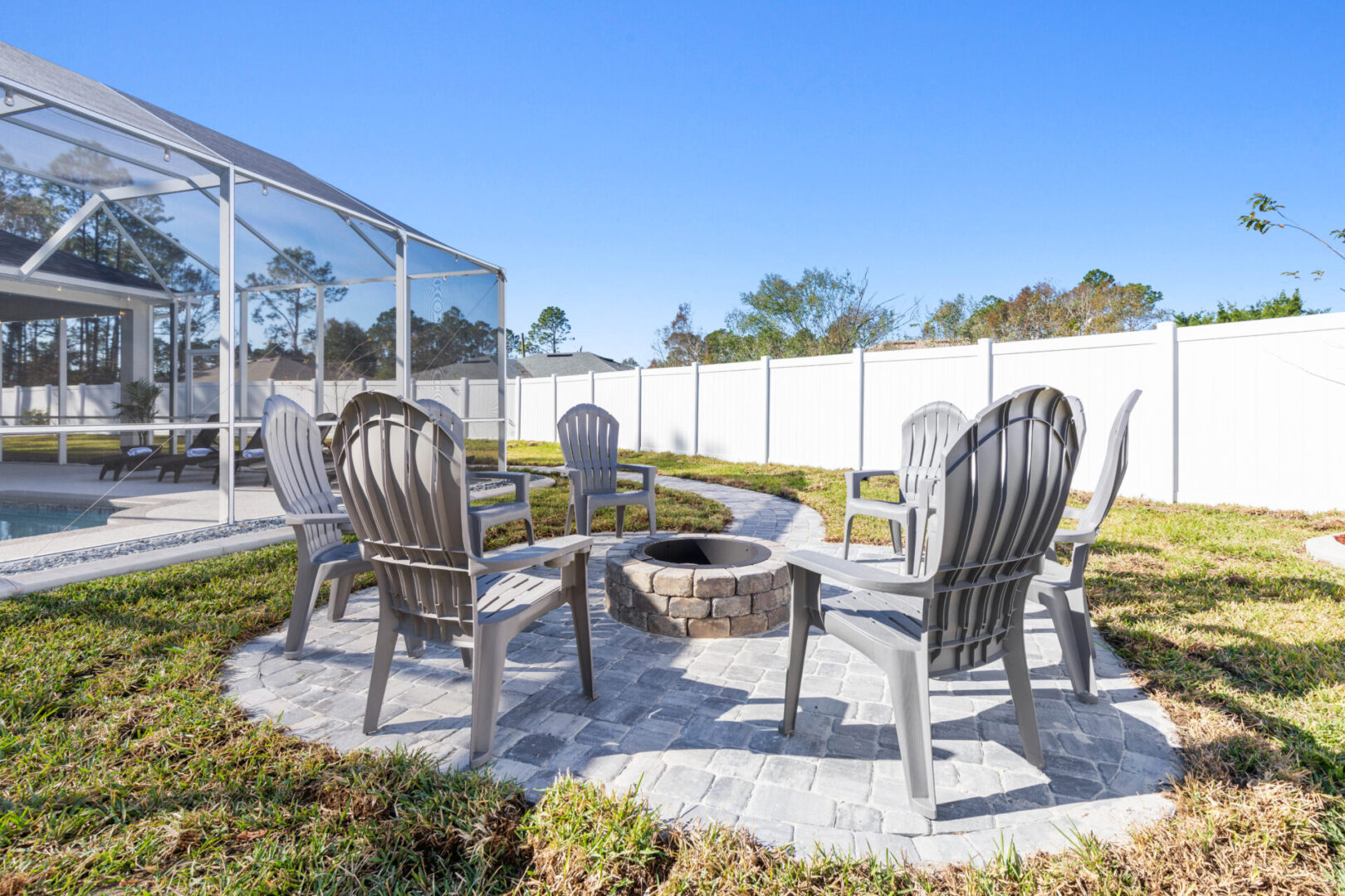 A fire pit with chairs around it in the back yard.