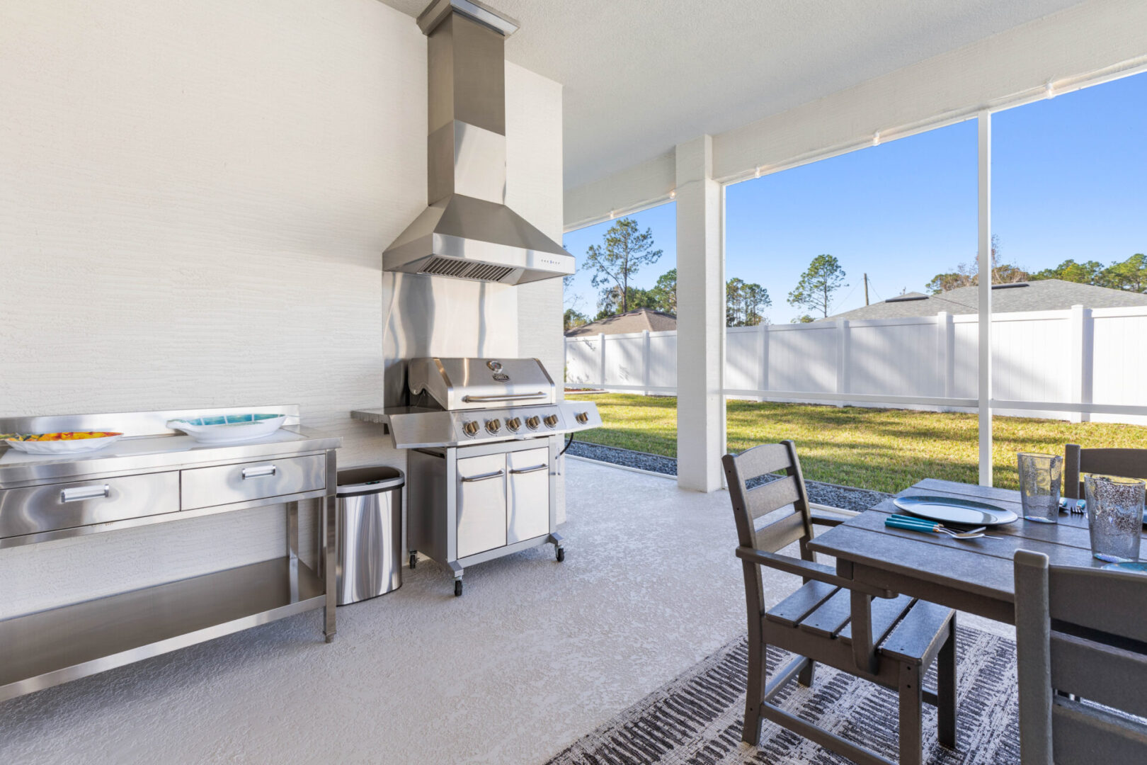 A large outdoor grill and table in the middle of an outside patio.